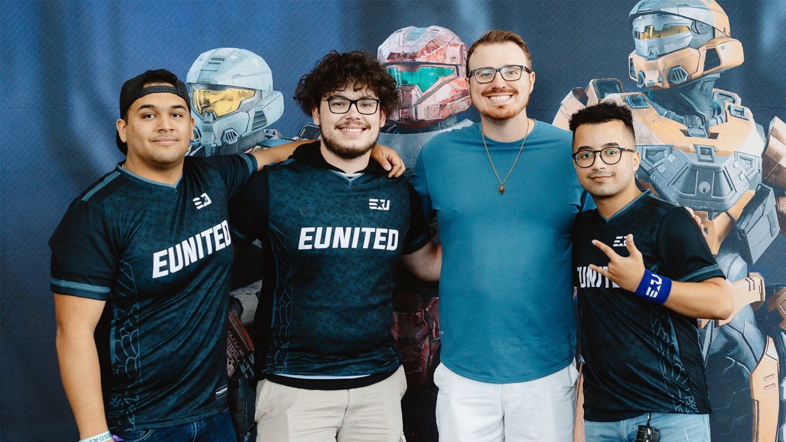 Three interns wearing eUnited jerseys stand with Matt Pothoff in front of a Halo backdrop.