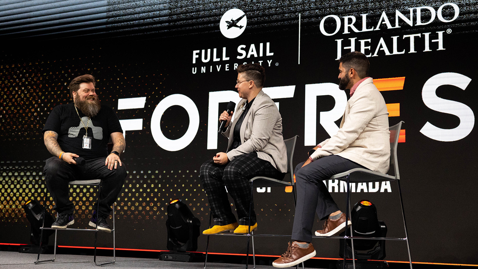 Full Sail Director of Esports Growth & Development Bennett Newsome on stage in the Fortress with Orlando Health representatives Dominique Smith and Skylar Richards.