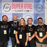 Five people wearing black shirts and badges that read "production" while standing in front of a step and repeat featuring the Super Girl Gamer pro logo and event sponsor logos.